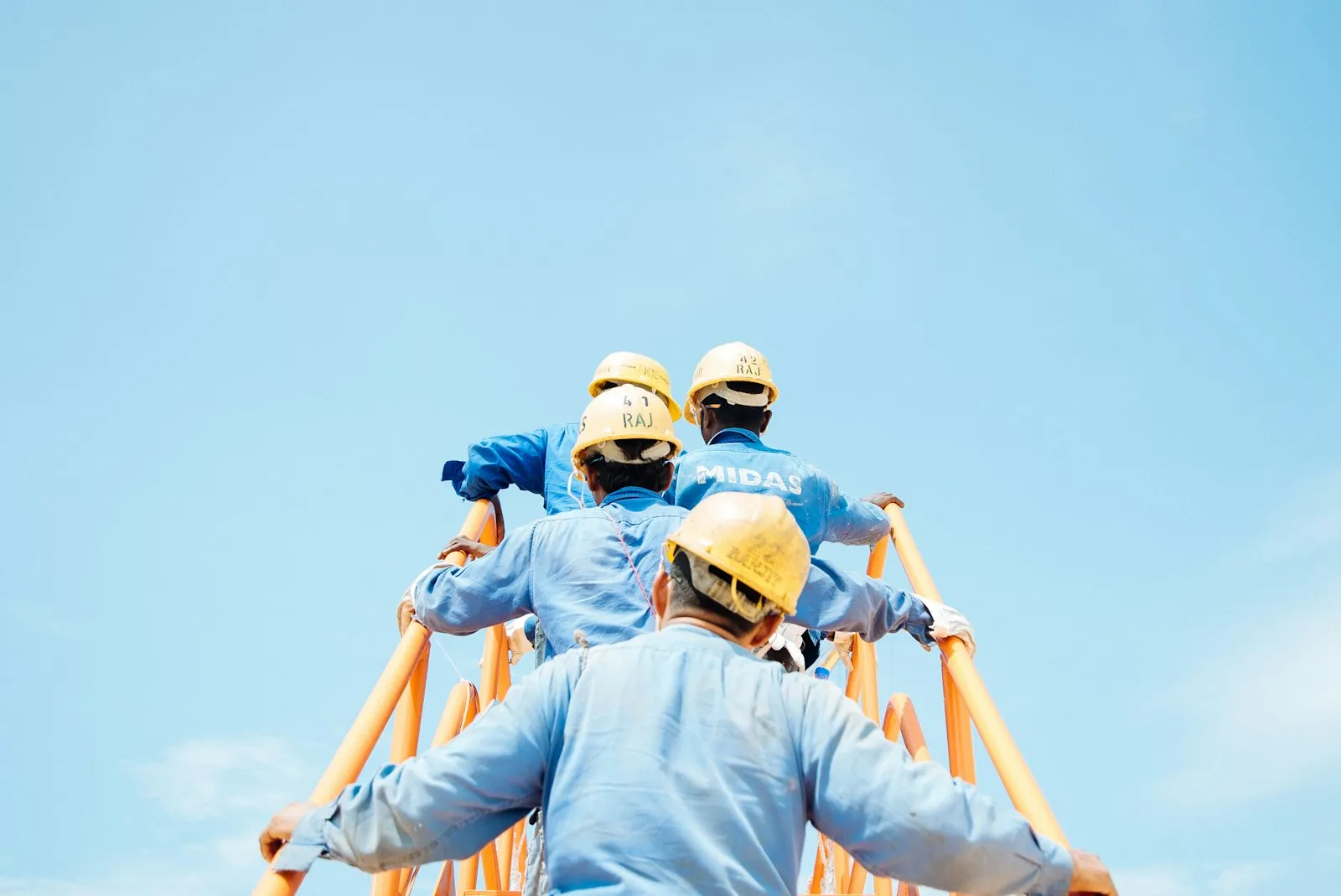 Team of construction workers in hard hats and hi-vis PPE looking up at a worksite
