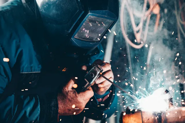 Worker welding on a manufacturing floor with protective equipment